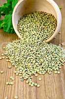 Lentils green in wooden bowl on board