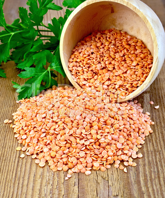 Lentils red in wooden bowl on board
