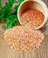 Lentils red in wooden bowl on board