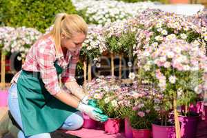garden center woman kneeling by potted flowers