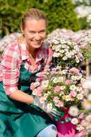 garden center woman holding potted flowers smiling
