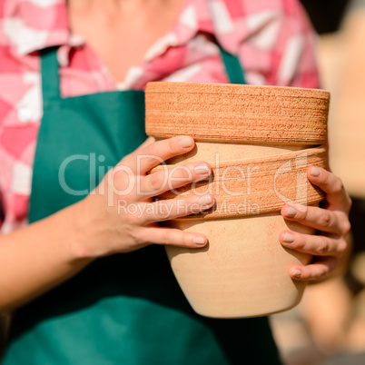 close-up hands holding two clay pots