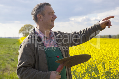 Farmer with shovel controls his canola field