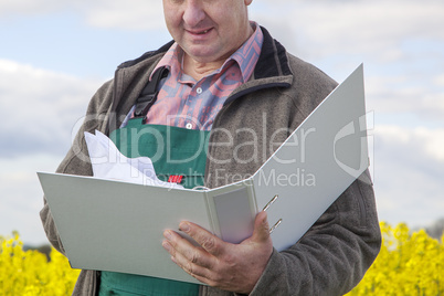 Farmer with file folders in rape field