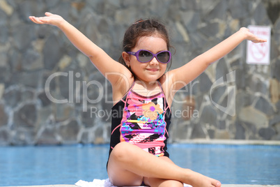 Happy little girl with open arms outside the pool