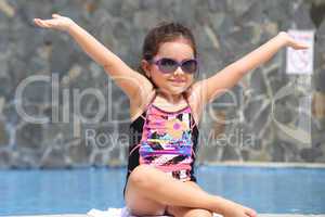 Happy little girl with open arms outside the pool