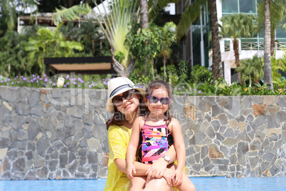 Girl with her mother outside swimming pool enjoying the summerwi