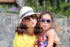 Portrait of mother and daughter giving a kiss to the camera. Foc