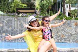 Mother and daughter happy in the pool with open arms enjoying th