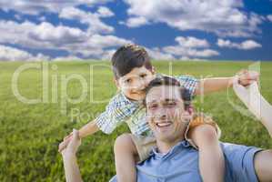 Mixed Race Father and Son Playing Piggyback on Grass Field
