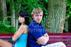 Mann und Frau sitzen Rücken an Rücken auf der Parkbank