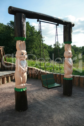 Strange child's swing with wooden sculptures