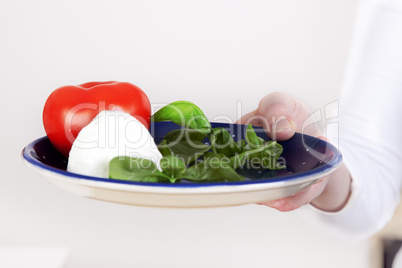 Hand holding plate with salad
