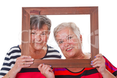 Zwei Seniorinnen schauen durch Bilderrahmen