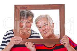 Zwei Seniorinnen schauen durch Bilderrahmen