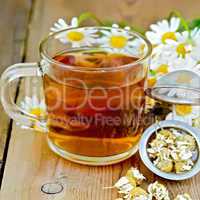 Herbal chamomile tea in a mug with strainer on the board