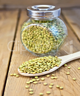 Lentils green in jar and spoon on board
