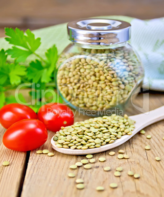 Lentils green in jar and spoon with tomatoes on board