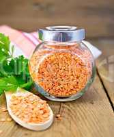 Lentils red in jar and spoon on board with parsley