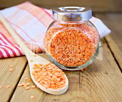 Lentils red in jar and spoon with napkin on board