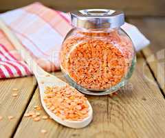 Lentils red in jar and spoon with napkin on board