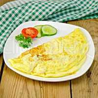 Omelet with vegetables and green napkin on board