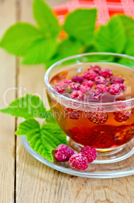 Tea with raspberries in glass cup and napkin on board