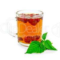 Tea with raspberry and green leaf in glass mug