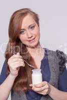 Frau isst einen Joghurt mit dem Löffel