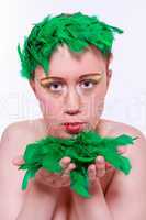 Modell mit bunten Make-up hält grünen Federn