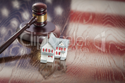 Small House and Gavel on Table with American Flag Reflection