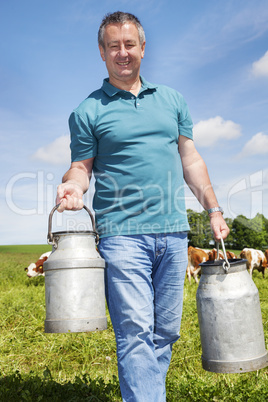 farmer with milk churns at his cows