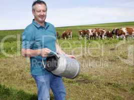 farmer with milk churns at his cows