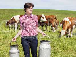 Farmer with milk churns at their cows