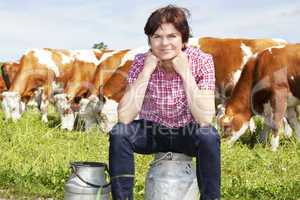 Farmer with milk churns at their cows