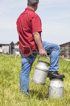 farmer with milk churns at his cows