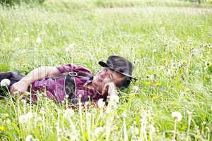 Man with hat lying in the spring meadow