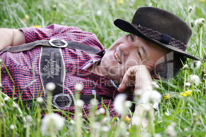 Man with hat lying in the spring meadow