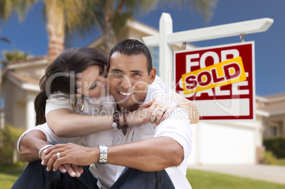 Hispanic Couple, New Home and Sold Real Estate Sign