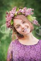 Beautiful cute girl in a wreath of lilacs