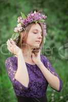 Beautiful cute girl in a wreath of lilacs