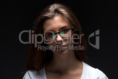 Serious teenager girl in shadow with glasses