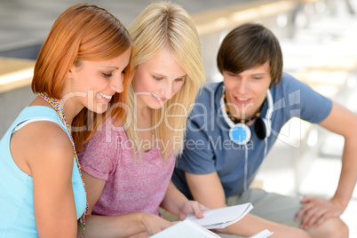 Three college friends studying looking into book