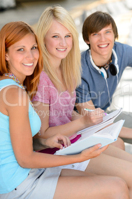 Smiling student friends sitting together studying