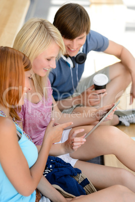 Three college students looking at tablet sitting