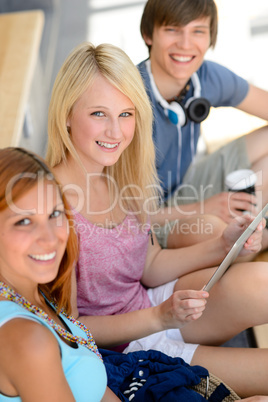 Three student friends with tablet smiling camera