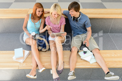 Three college student friends with tablet and book