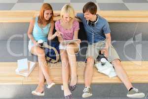 Three college student friends with tablet and book