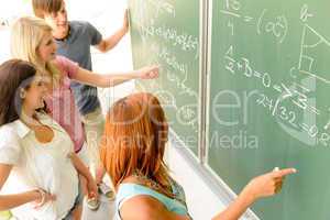 Math student write on green chalkboard classmates