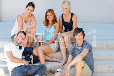Students group sitting on school stairs smiling